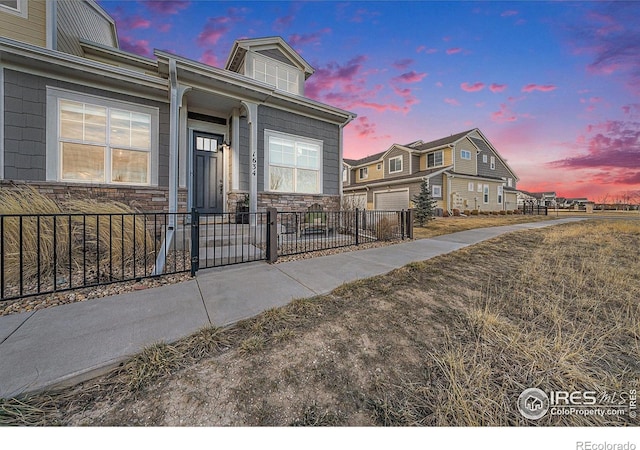 view of front of property with a garage, stone siding, and a fenced front yard