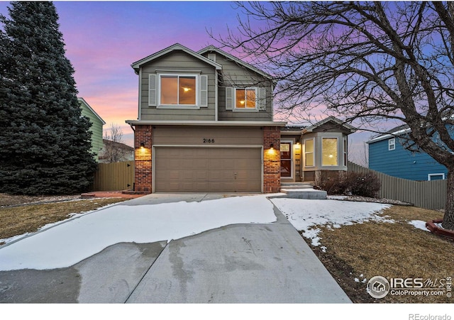 view of front of house with driveway, an attached garage, fence, and brick siding