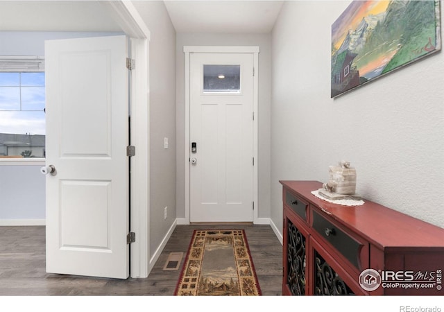 doorway featuring dark wood-type flooring, visible vents, and baseboards