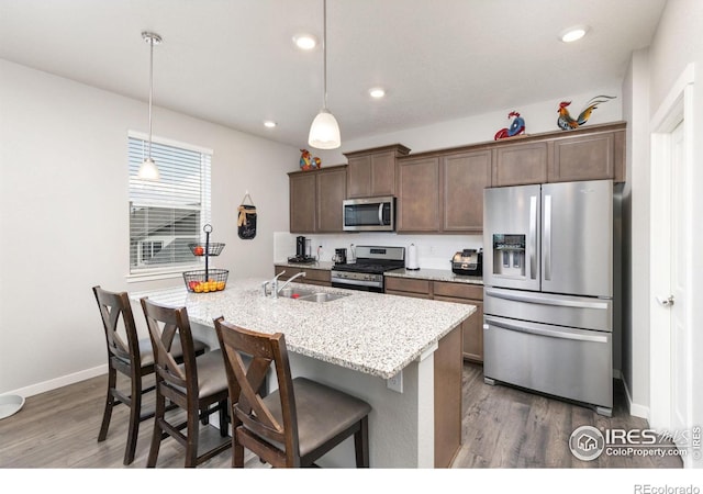 kitchen featuring appliances with stainless steel finishes, a breakfast bar area, hanging light fixtures, and an island with sink