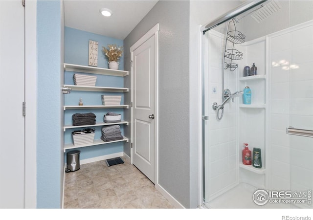 full bath with a shower stall and baseboards