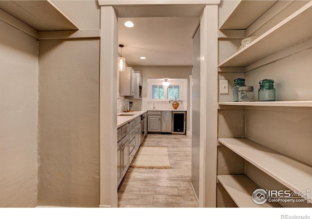 kitchen with wine cooler, decorative light fixtures, a sink, light countertops, and stainless steel dishwasher