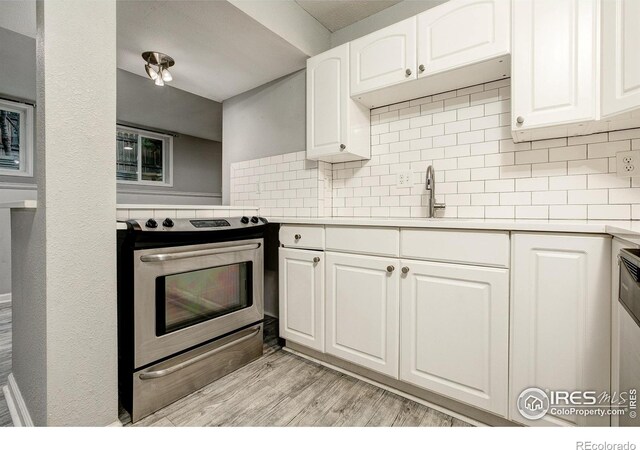 kitchen with electric stove, light countertops, decorative backsplash, light wood-style floors, and white cabinetry