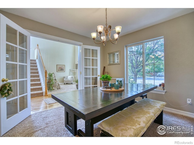 dining area featuring baseboards, french doors, stairway, and an inviting chandelier