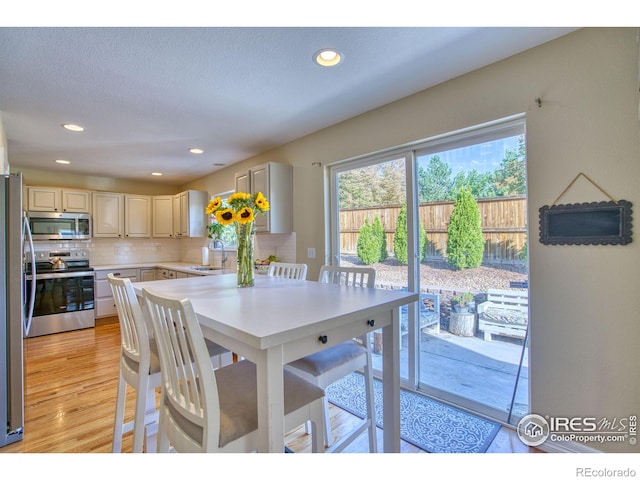 dining area with light wood finished floors, a textured ceiling, and recessed lighting