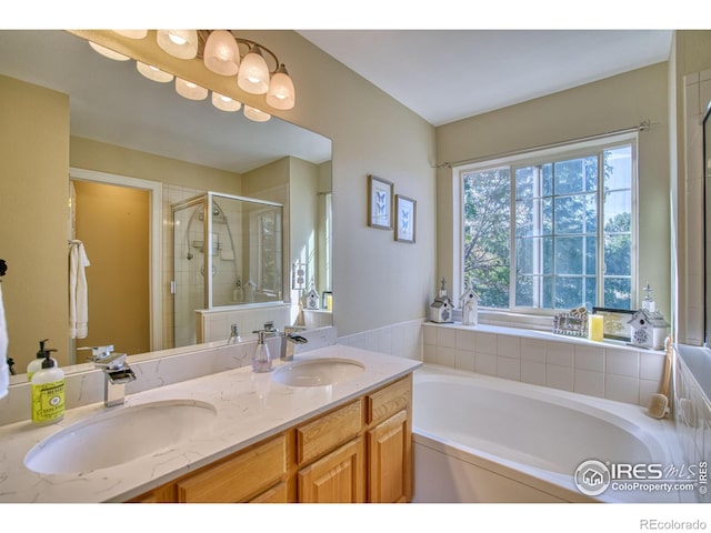 bathroom with double vanity, a garden tub, a shower stall, and a sink