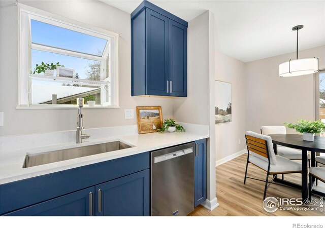 kitchen featuring a sink, light countertops, stainless steel dishwasher, hanging light fixtures, and blue cabinetry