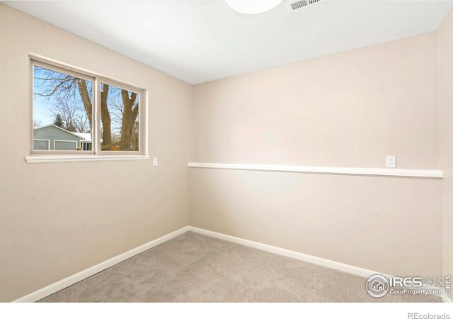 empty room featuring light carpet, visible vents, and baseboards