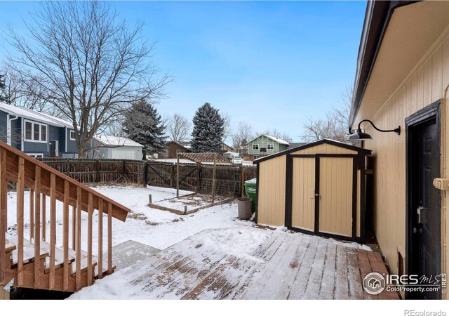 yard covered in snow with a fenced backyard, a storage unit, a wooden deck, and an outdoor structure