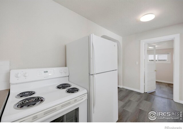 kitchen featuring white appliances, dark wood finished floors, and baseboards