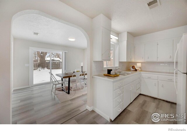 kitchen with white cabinets, visible vents, arched walkways, and light countertops