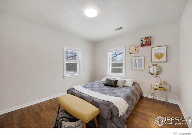 bedroom with visible vents, baseboards, and wood finished floors