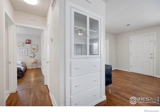 corridor with dark wood-style floors and baseboards