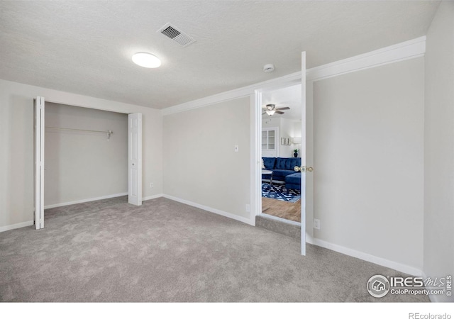 unfurnished bedroom featuring light carpet, a textured ceiling, visible vents, and baseboards