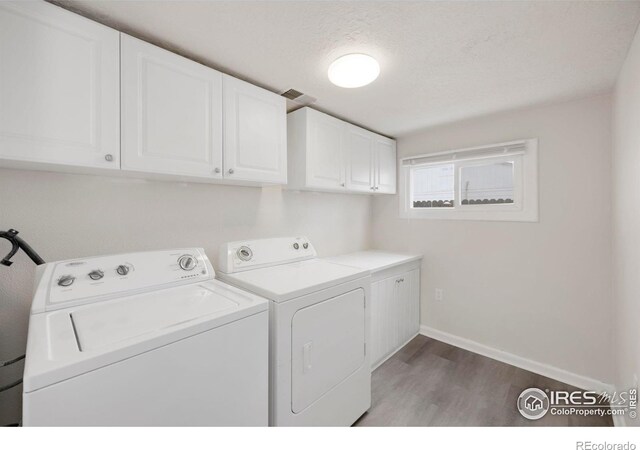 laundry room featuring cabinet space, visible vents, separate washer and dryer, wood finished floors, and baseboards