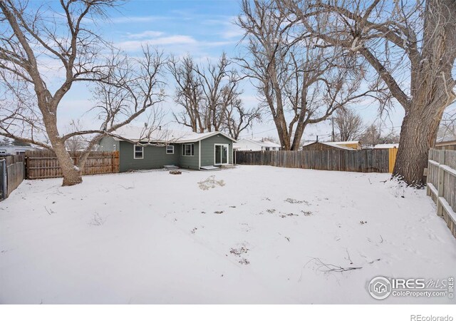 snow covered property featuring a fenced backyard