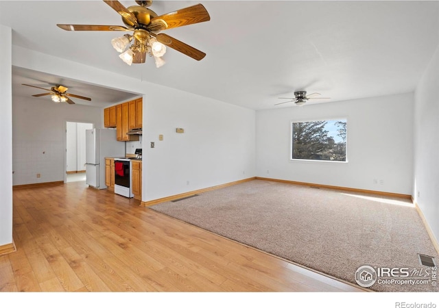 unfurnished living room featuring visible vents, light wood-style flooring, and baseboards