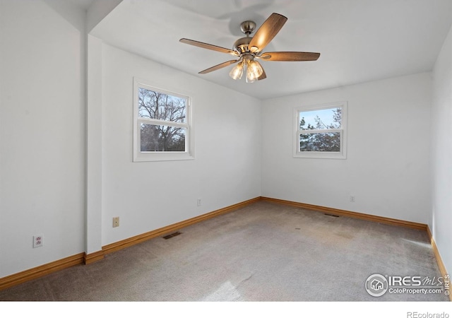 carpeted empty room featuring a wealth of natural light, visible vents, and baseboards