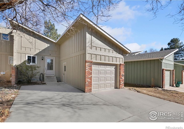 view of front of home featuring entry steps, a garage, brick siding, concrete driveway, and board and batten siding