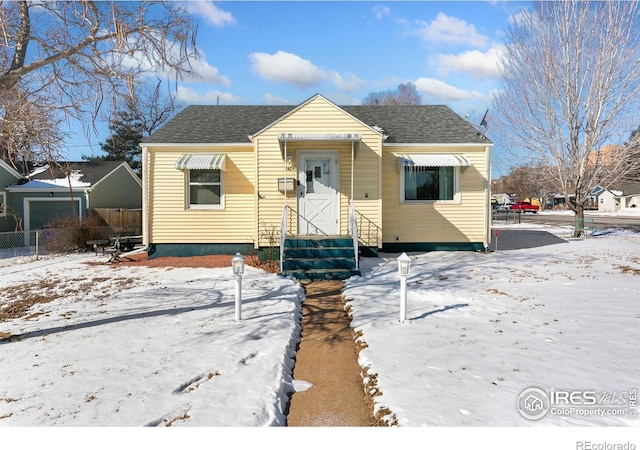 bungalow-style home with roof with shingles and fence