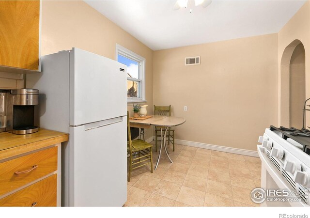 kitchen with white appliances, baseboards, visible vents, and arched walkways