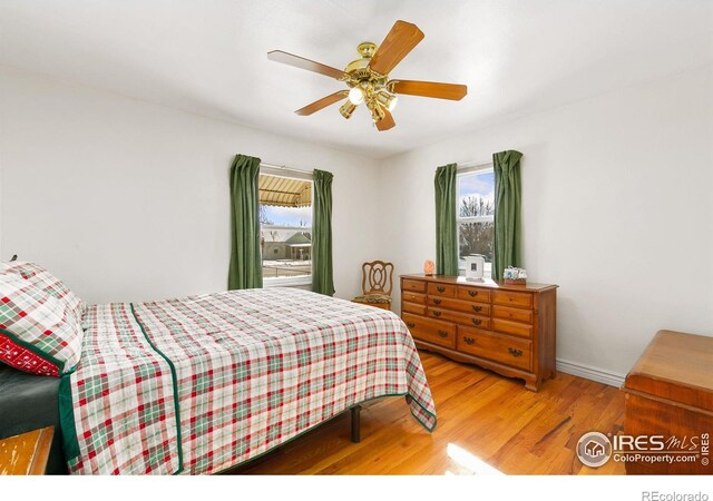 bedroom with a ceiling fan, multiple windows, baseboards, and wood finished floors