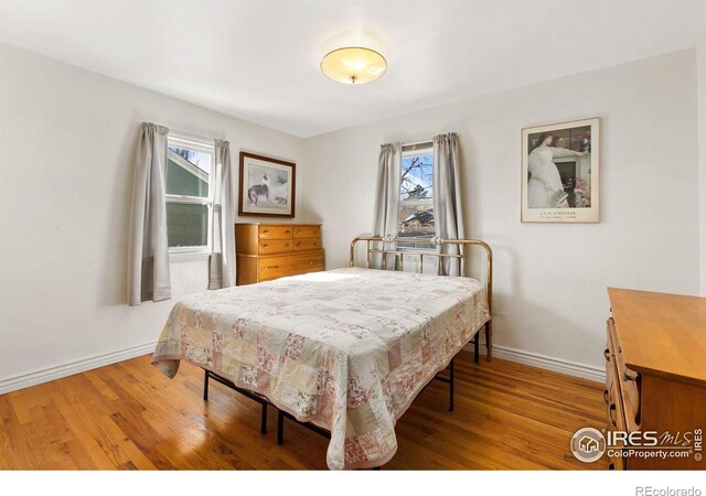 bedroom featuring multiple windows, baseboards, and wood finished floors