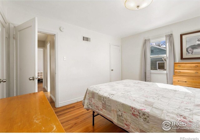 bedroom with wood finished floors, visible vents, and baseboards