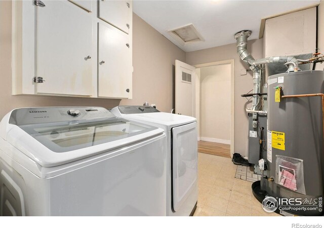 laundry area with separate washer and dryer, baseboards, water heater, cabinet space, and attic access