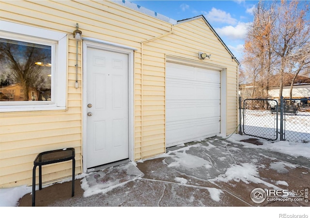 snow covered garage with a garage and fence