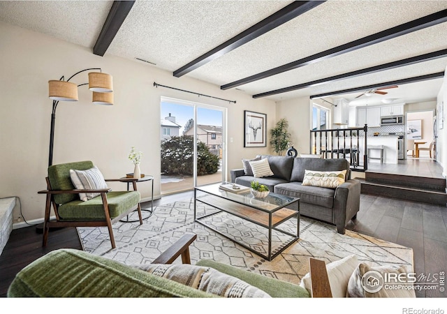 living room featuring light wood-style flooring, a ceiling fan, a textured ceiling, beamed ceiling, and baseboards