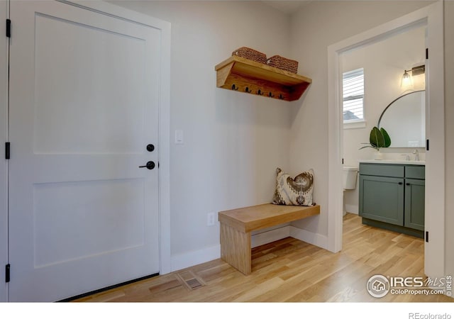 mudroom featuring light wood-style floors, baseboards, and a sink