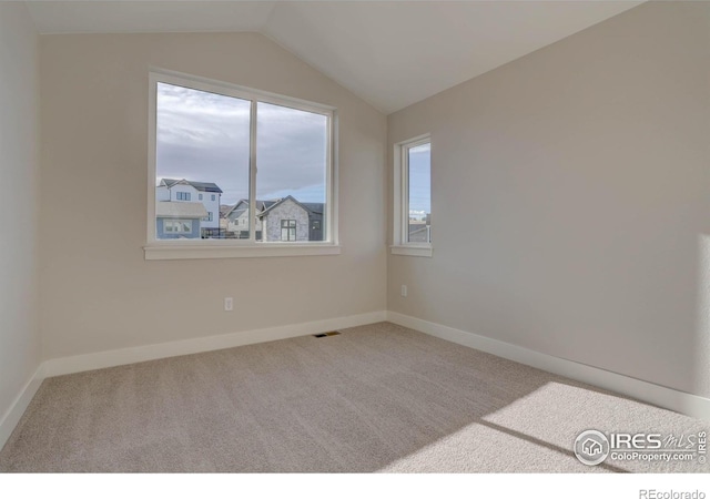 empty room featuring carpet, visible vents, vaulted ceiling, and baseboards