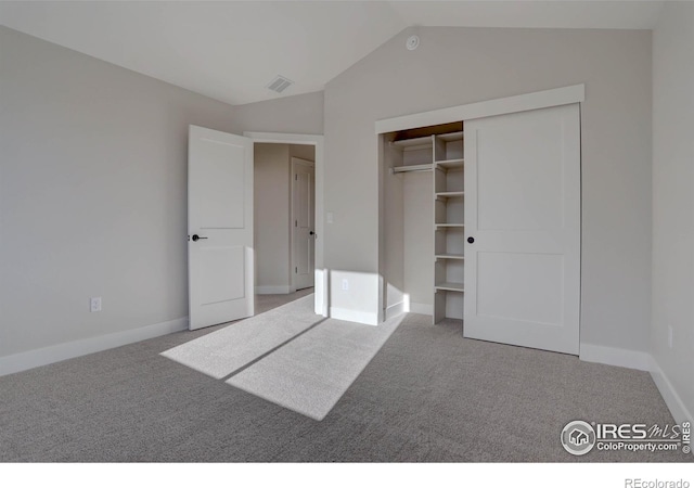 unfurnished bedroom with carpet, a closet, visible vents, and lofted ceiling