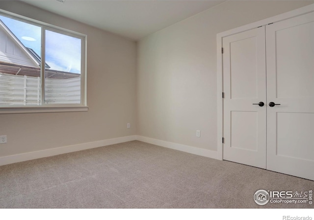 unfurnished bedroom featuring baseboards and light colored carpet