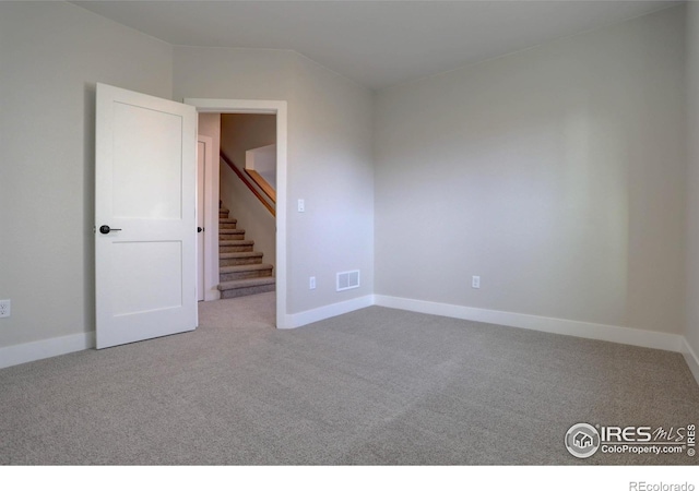 unfurnished room with light carpet, stairway, visible vents, and baseboards