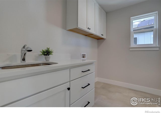 laundry area with washer hookup, a sink, cabinet space, and baseboards