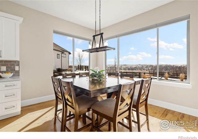 dining area with light wood finished floors and baseboards