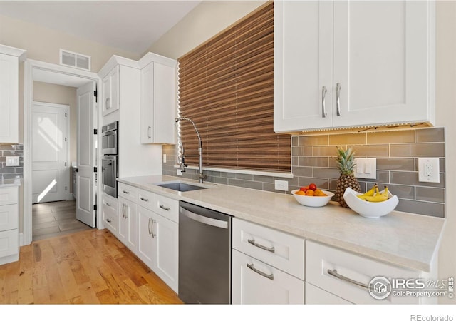 kitchen featuring stainless steel appliances, a sink, visible vents, white cabinets, and light wood finished floors