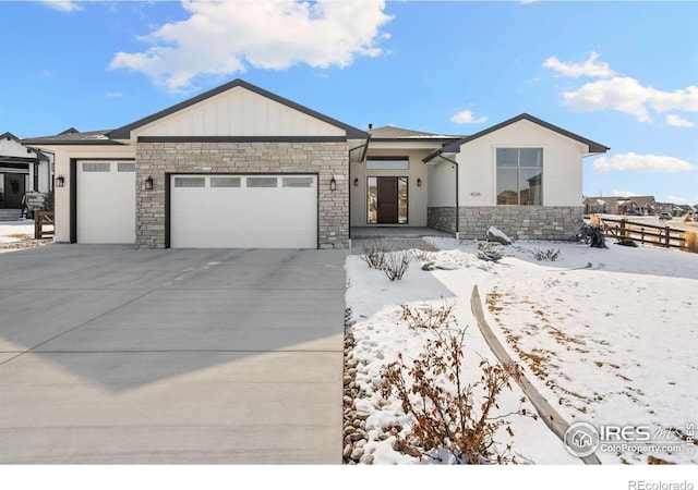 view of front of property featuring a garage, concrete driveway, board and batten siding, and stone siding