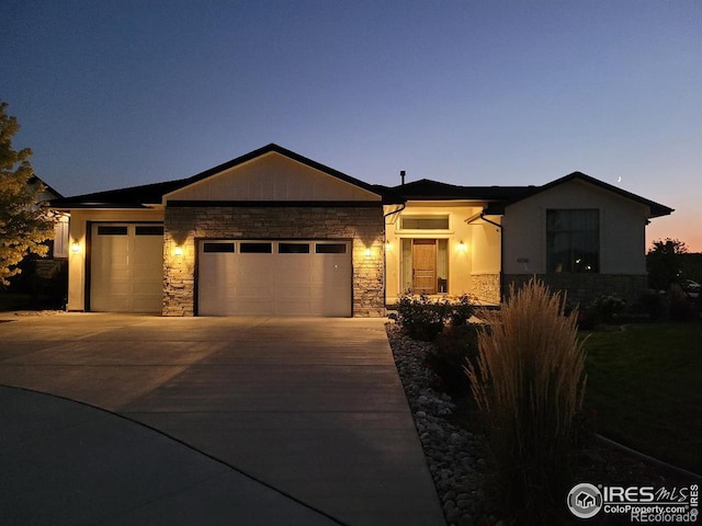 view of front facade featuring a garage, stone siding, and driveway