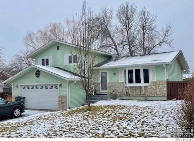 split level home with a garage, stone siding, and driveway