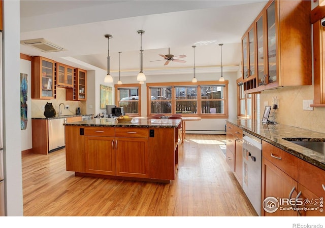 kitchen with glass insert cabinets, dark stone counters, brown cabinetry, and stainless steel dishwasher