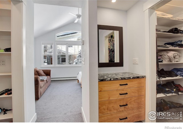 spacious closet featuring lofted ceiling, ceiling fan, baseboard heating, and light colored carpet