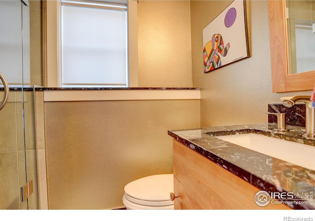 full bathroom featuring toilet, a shower with shower door, and vanity