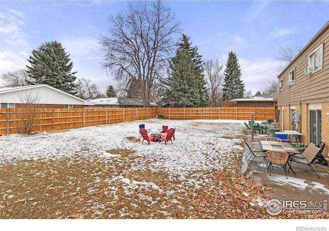 snowy yard featuring outdoor dining area and a fenced backyard