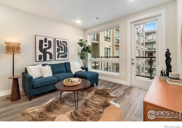 living room with recessed lighting, visible vents, baseboards, and wood finished floors