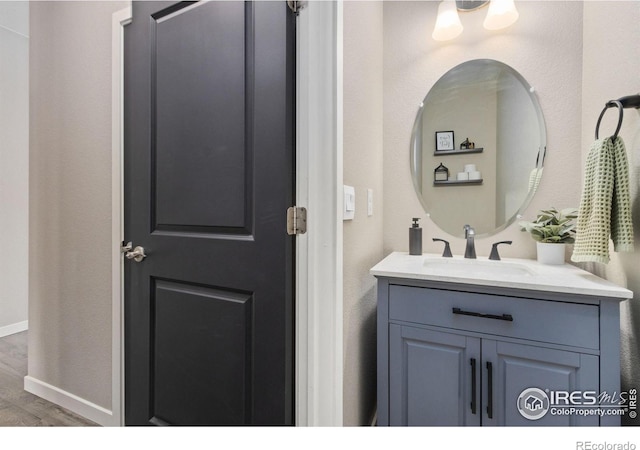 bathroom featuring baseboards, wood finished floors, and vanity