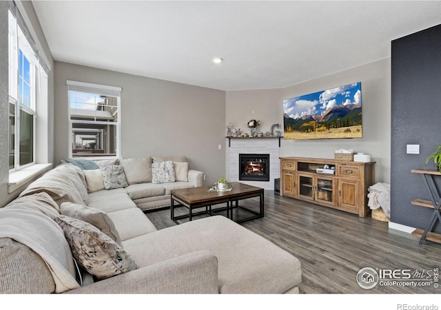 living room featuring dark wood-style floors, recessed lighting, a glass covered fireplace, and baseboards