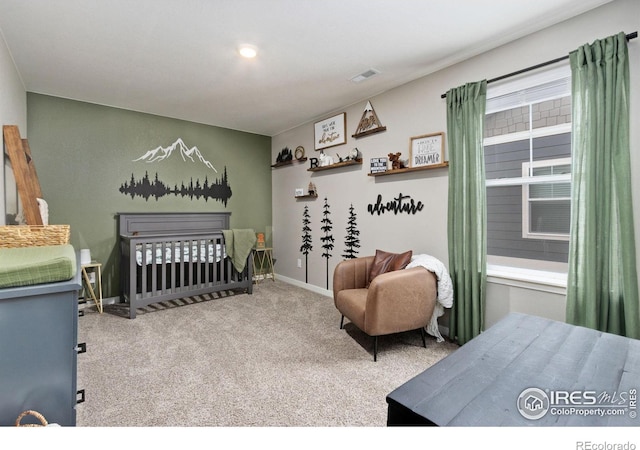 carpeted bedroom featuring visible vents, a crib, and baseboards